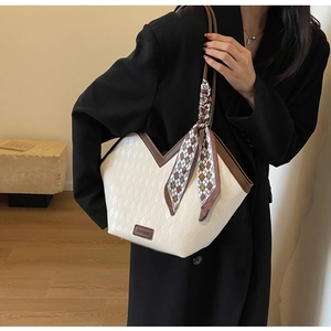 Detail of quilted tote bag with silk scarf accessory and fashion text logo