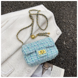 Detail of light blue tweed bag featuring a golden rotary lock and adjustable ball chain
