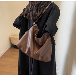 Side view of a large brown hobo bag in lychee leather worn by a model for a chic look