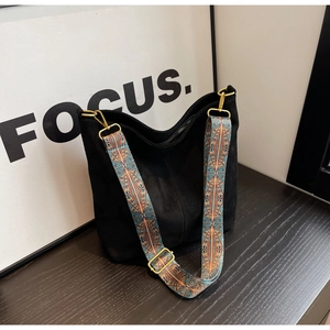 Detail of black suede tote bag with bohemian ethnic patterned wide shoulder strap