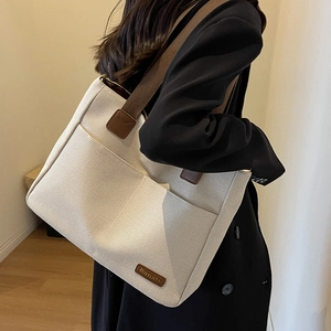 Large beige canvas tote bag with front pockets and brown strap for stylish daily commuting