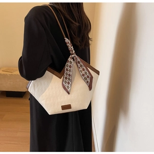 Detail of cream quilted tote bag with brown leather trim and plaid silk scarf decoration