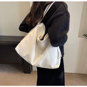 Detailed texture of white large capacity leather tote bag on model's shoulder