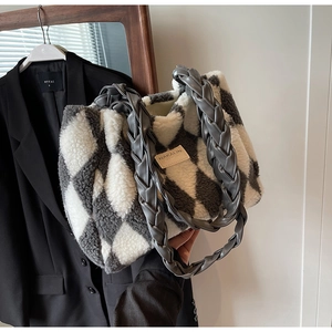 Close-up of black and white plush tote bag featuring diamond patterns and woven handles
