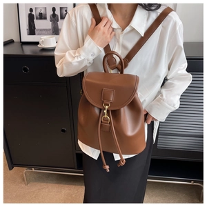 Détail d'un sac à dos en cuir marron avec fermeture à cordon et rabat arrondi en intérieur
