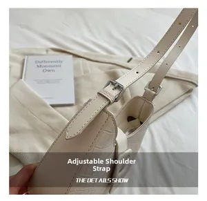 Detail of adjustable pin-buckle shoulder strap and cream crocodile embossed texture