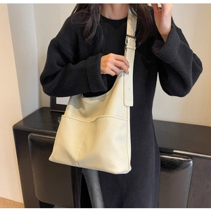 Détail du grand sac seau crème avec texture grainée et poches frontales pratiques