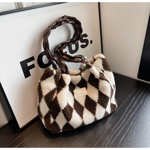 Detail of checkered plush tote bag featuring braided leather handles and tactile texture