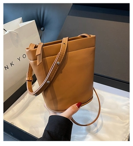 Détail d'un sac seau en cuir marron avec bandoulière réglable sur une boîte cadeau