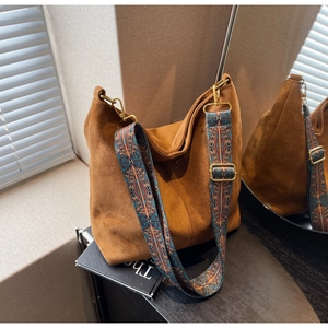 Detail of a brown suede hobo bag featuring a vintage bohemian patterned wide strap