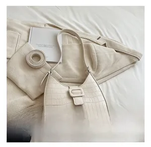 Detail showing creamy white half-moon bag with crocodile embossing and buckle detail