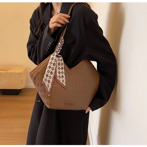 Close-up of brown quilted tote bag with V-shaped design and decorative silk scarf