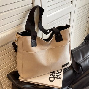 Large beige canvas tote bag with black handles and metal D-ring for daily commute