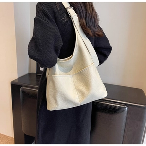Gros plan d'un cabas en cuir beige avec texture grainée et poches avant pour le quotidien