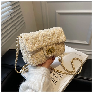 Detailed macro view of the cream tweed texture and golden metal twist lock on a mini bag