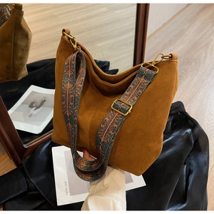 Detail of brown suede tote with geometric patterned strap and gold hardware
