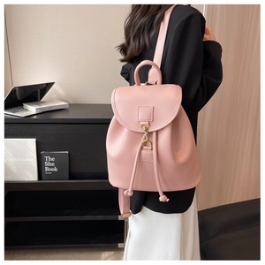 Détail d'un sac à dos en similicuir rose avec boucle dorée et fermeture à cordon