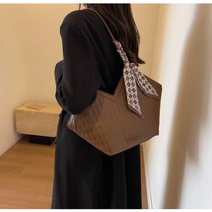 Close-up of brown woven leather tote bag featuring a checkered scarf and fashion tag