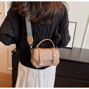 Brown leather crossbody bag detail featuring stylish wide patterned shoulder strap