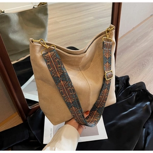 Detail of beige suede hobo bag with a wide bohemian ethnic pattern jacquard strap