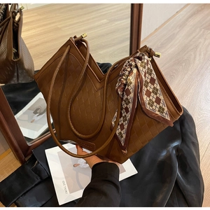 Close-up of brown tote bag featuring woven texture and decorative fashion scarf