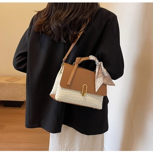 Detail of white woven bag with brown leather flap, gold lock and decorative scarf