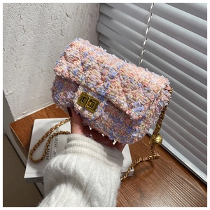 Close-up of pink tweed chain bag featuring a gold ball length adjuster and textured finish