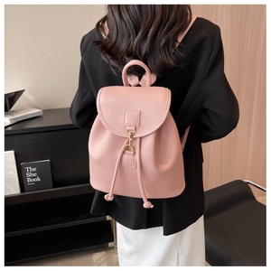 Vue arrière du modèle portant un sac à dos en cuir rose avec boucle dorée et cordon