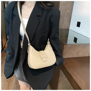 Detail of beige faux crocodile leather shoulder bag featuring a half-moon shape and buckle