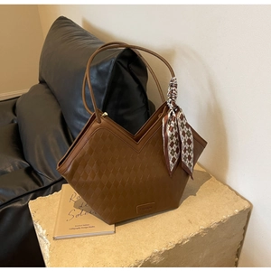 Detail of brown geometric quilted tote bag with silk scarf on leather sofa