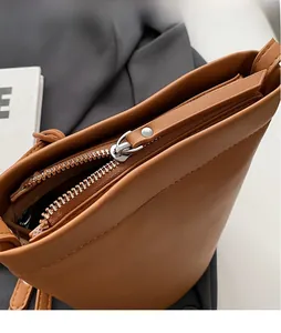 Gros plan sur la fermeture éclair en métal et la texture cuir marron du sac