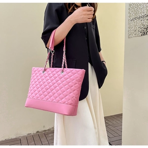 Détail latéral d'un sac cabas rose matelassé avec bandoulière chaîne sur un mannequin