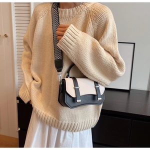 Close-up of stylish black and white crossbody bag with wide geometric woven strap