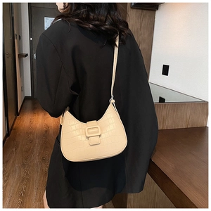 Detailed view of cream crocodile-embossed hobo bag featuring a large decorative square buckle