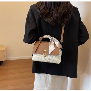 Detail of woven texture handbag with printed silk scarf and gold metal hardware