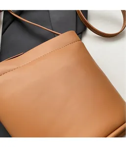 Détail du sac seau en cuir marron avec coutures soignées et fine bandoulière en cuir
