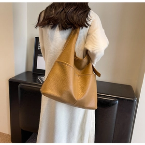 Détail d'un grand sac hobo en cuir grainé marron avec une large bandoulière souple