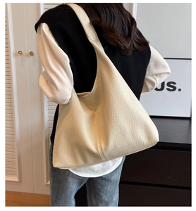 Detail of soft cream leather tote bag showing grainy texture and seamless shoulder strap