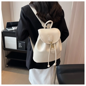 Photo lifestyle d'un mini sac à dos blanc cassé avec boucles dorées et cordon de serrage