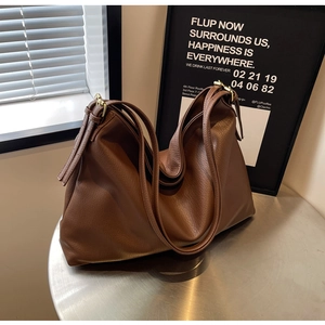Detail of large brown hobo bag with pebble leather texture and gold metal buckle