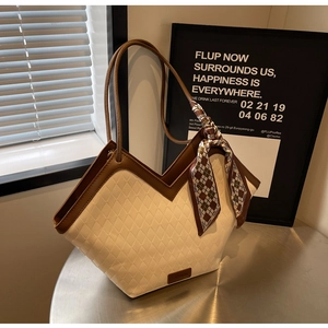 Detail of quilted tote bag with color contrast handles and decorative silk scarf