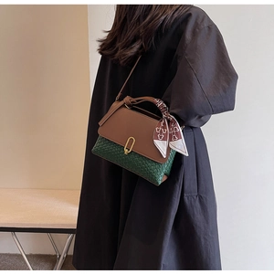 Detail of brown leather flap and green woven body with decorative scarf and metal lock