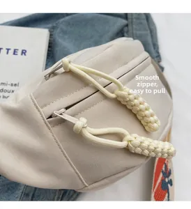 Detail of beige canvas waist bag with smooth zipper and woven decorative pullers