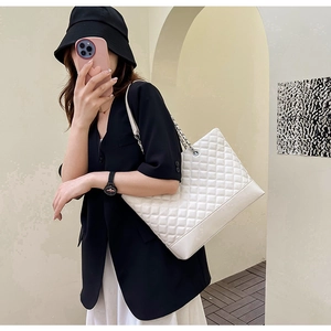 Close-up of white quilted tote bag featuring silver chain strap and minimalist design