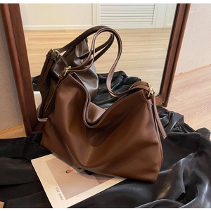 Detailed view of dark brown pebbled leather texture and adjustable gold hardware on tote