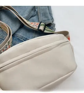 Detail of off-white canvas crossbody bag with floral embroidery wide shoulder strap