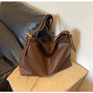 Detail of a large brown hobo bag with pebble leather texture and tassel decoration