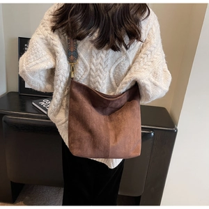 Close-up of brown suede hobo bag featuring ethnic jacquard wide shoulder strap and gold hardware