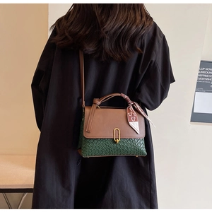 Model view of a vintage crossbody bag with green weave and brown leather stitching