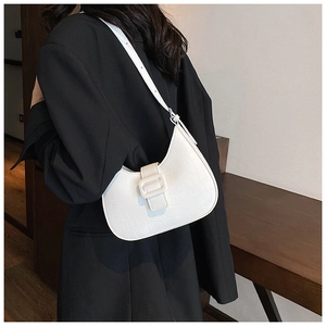 Close-up of white crocodile pattern underarm bag with large square buckle on a model